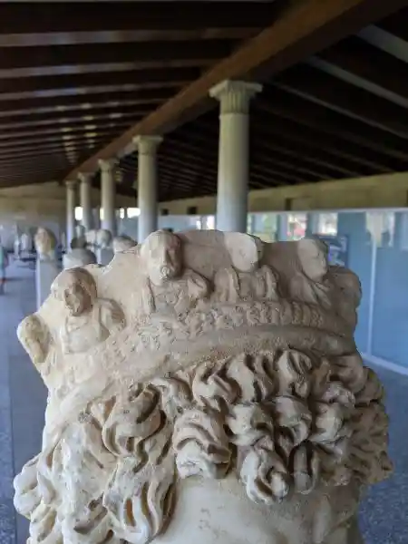 Rear view of marble priest portrait showing elaborate laurel wreath and carved relief figures